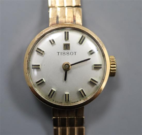 A ladys 9ct gold Tissot manual wind wrist watch, on a 9ct gold strap.